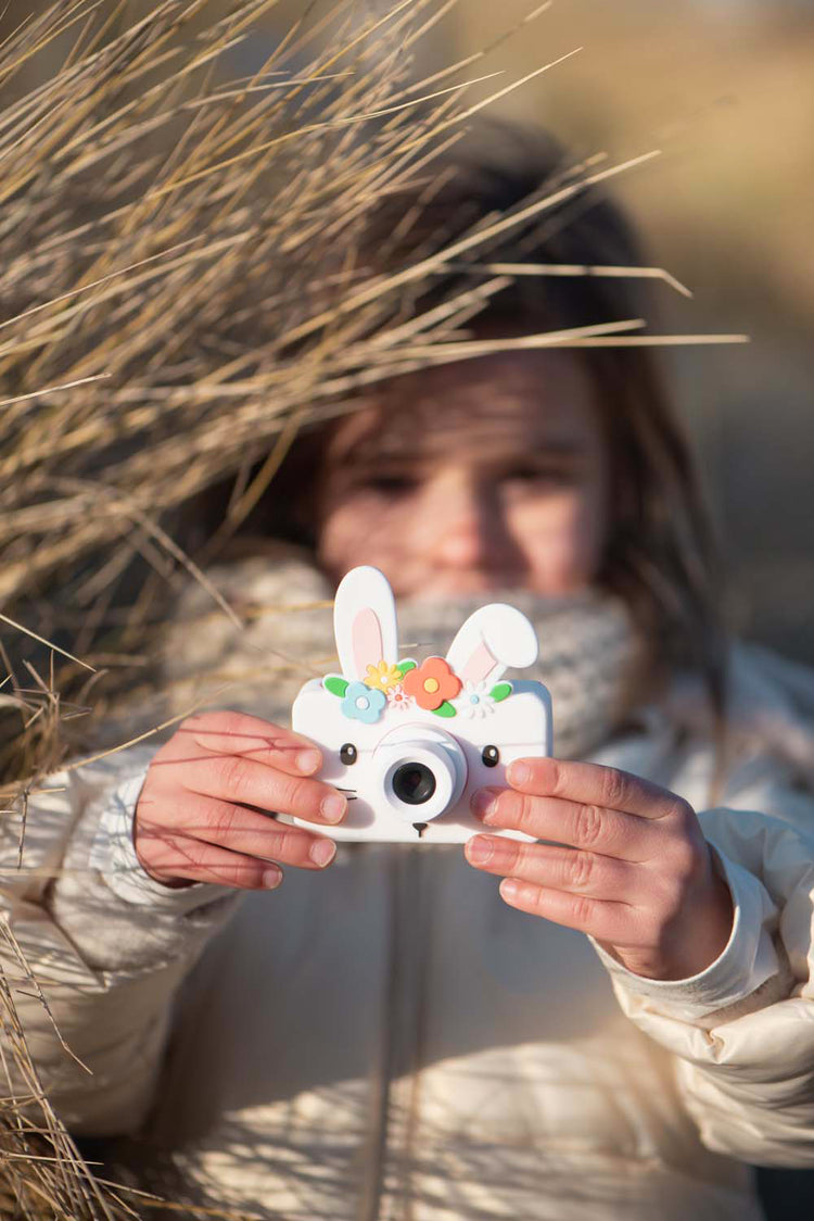 Enfant jouant en extérieur avec son appareil photo numérique lapin – idéal pour explorer et capturer des souvenirs