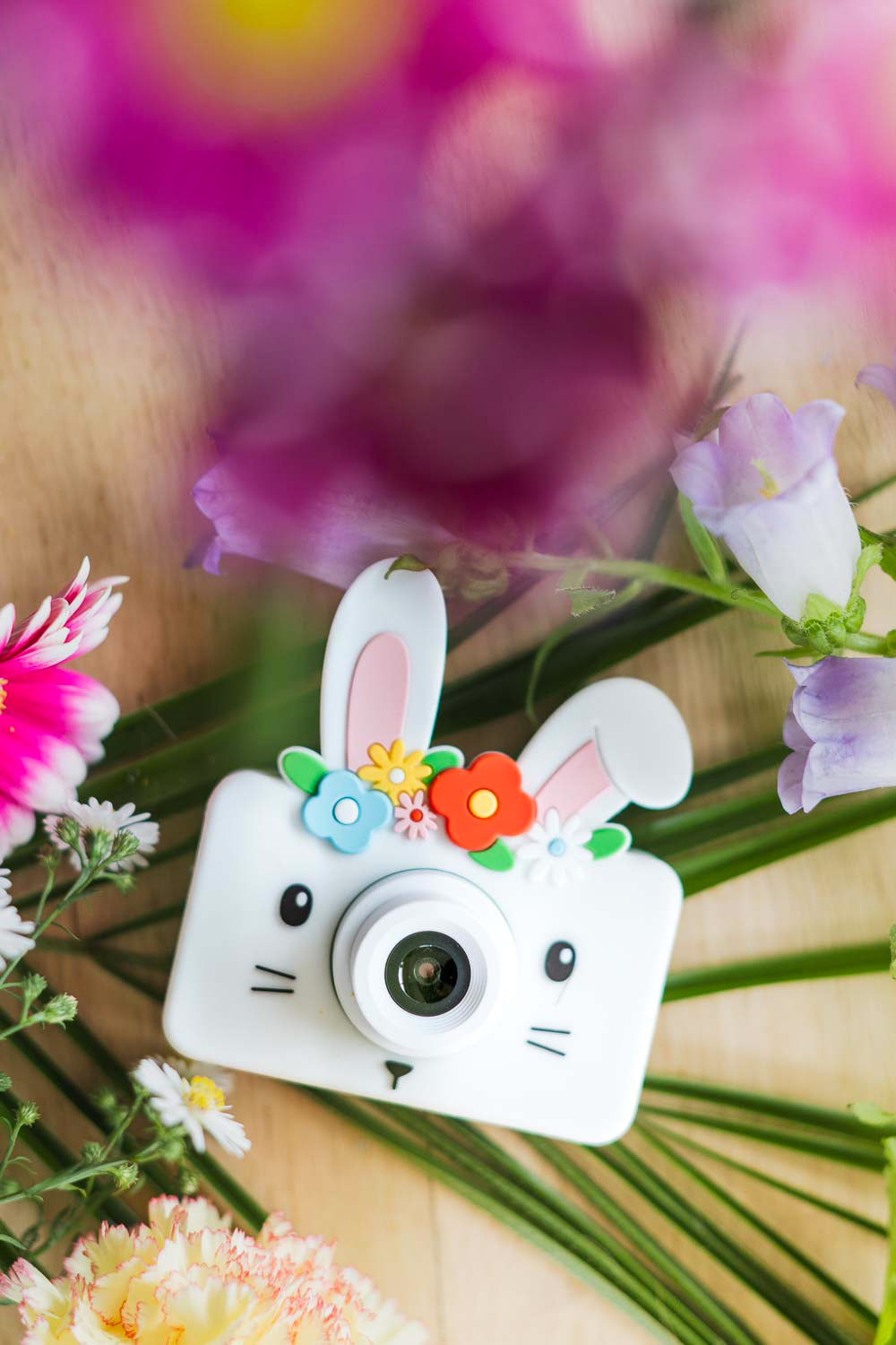 Gros plan sur l’appareil photo numérique lapin pour enfant entouré de fleurs printanières