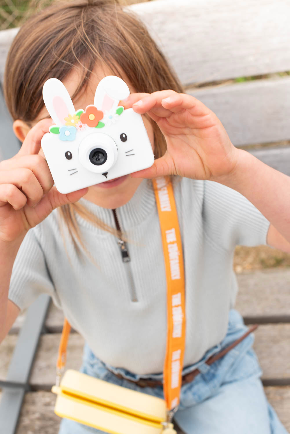 Enfant utilisant l’appareil photo numérique lapin pour capturer un moment spécial, avec sac de transport en silicone.