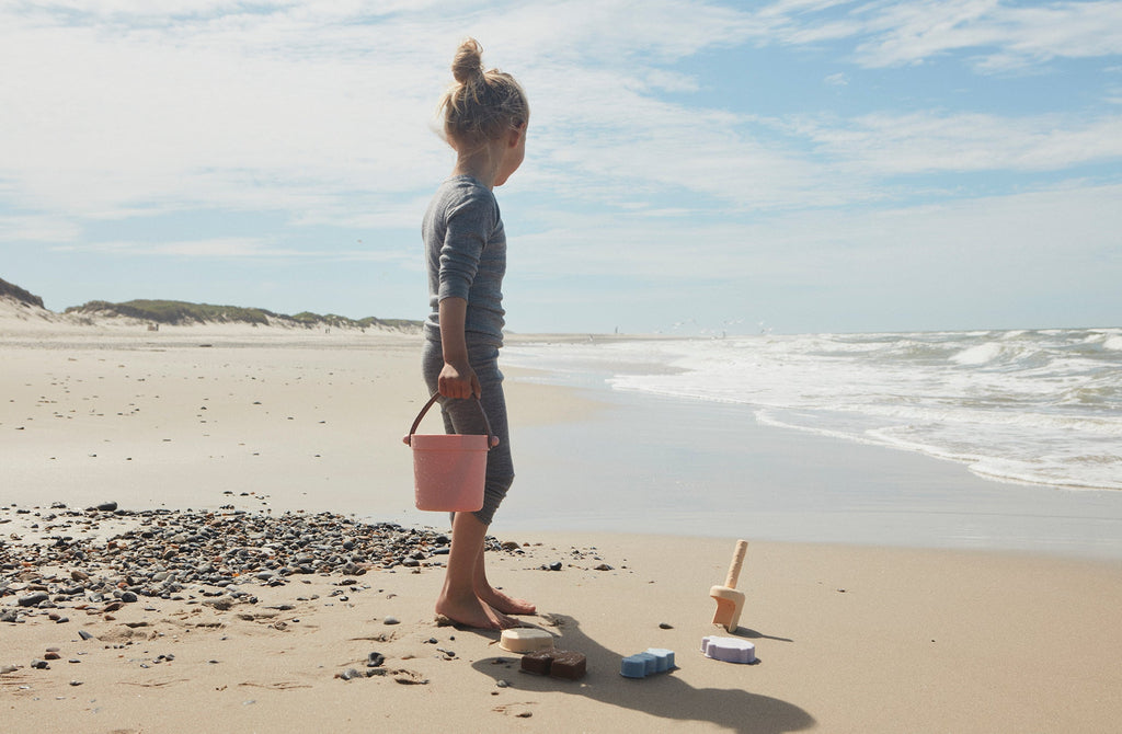 Petite fille s'amusant sur la plage avec le set de jouets de plage pour enfant OYOY Mini. En silicone, léger et résistant.