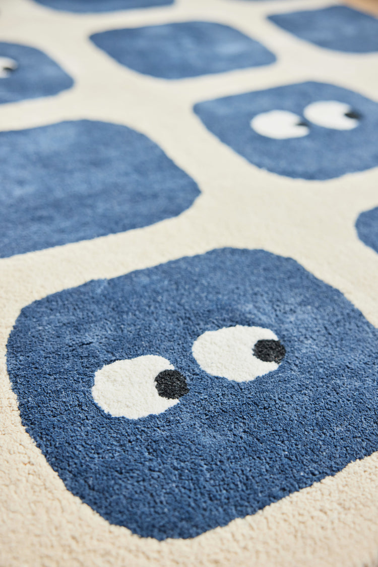 Bleuu-studio Tapis en coton bio pour chambre d'enfant. Sain, doux, moelleux. Epaisseur idéal pour limiter la poussière. Zoom sur un motif avec yeux amusants. Bleu marine.