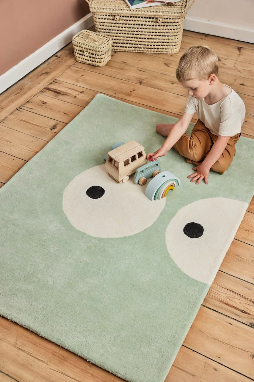 Zoom sur le motif du tapis Zoeils vert pâle en coton bio pour chambre enfant. Bleuu Studio, marque française.