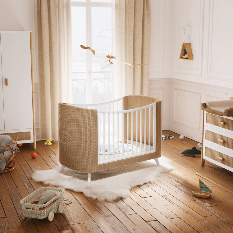 Lit bébé évolutif en rotin naturel dans une chambre chaleureuse